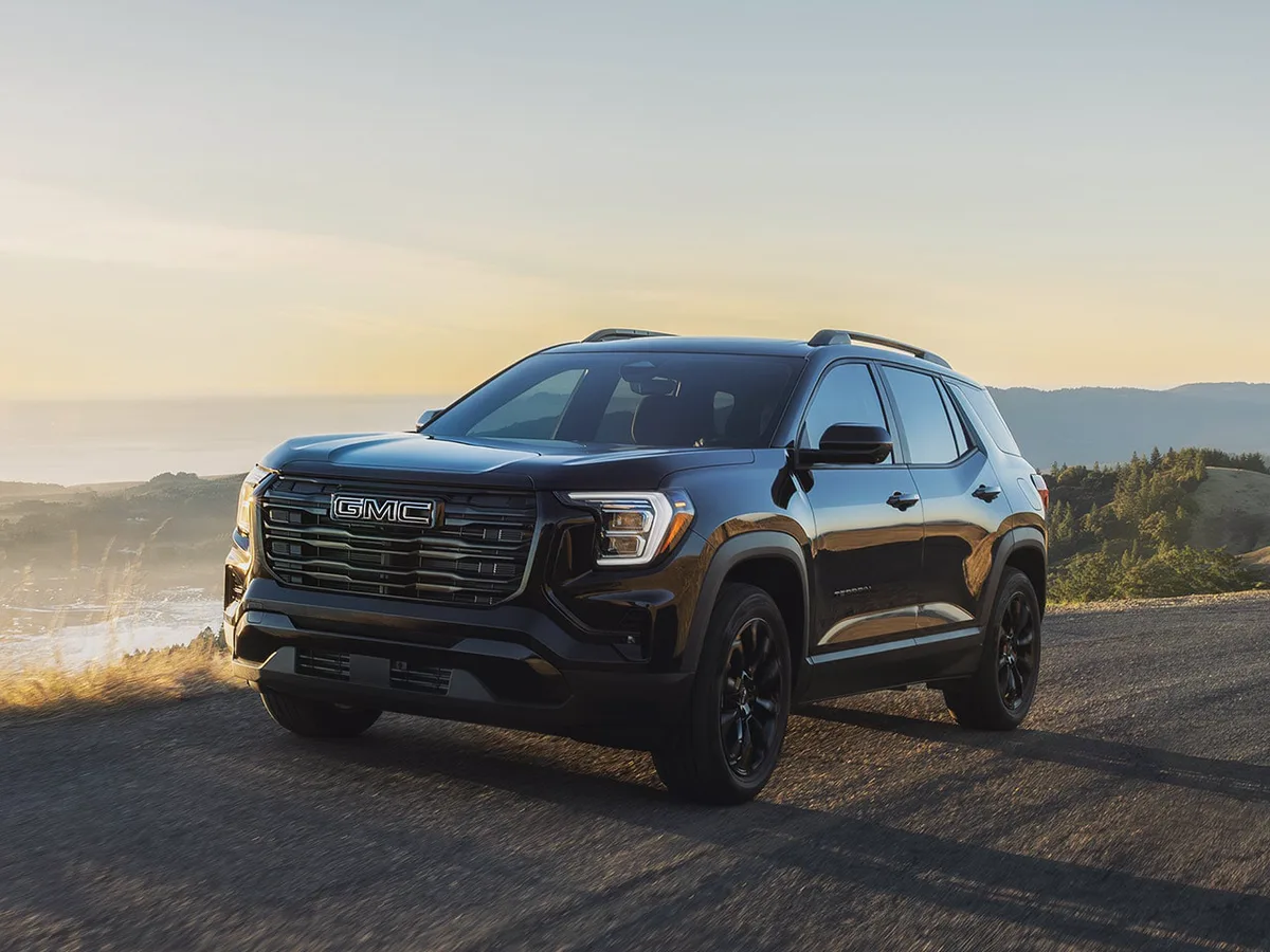 A Black GMC Acadia AT4 Parked On a Winding Road At Sunset with a Hazy Landscape in the Background